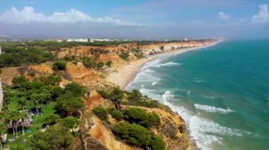 Praia da Falesia plajı, Algarve, Portekiz. Praia da Falesia, Algarve Portekiz 'de beyaz kumsal ve turkuaz su ile. Praia da Falesia, Algarve, Portekiz 'deki renkli turuncu kayalıklar.