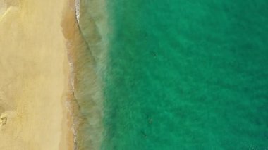 Fuerteventura Adası, İspanya, Kanarya Adaları 'nda turkuaz suyu olan bir sahil. Kum plajının havadan görünüşü, okyanus dokusunun arka plan döngüsü, İHA ile deniz dalgalarının yukarıdan aşağı görüntüsü. Fuerteventura, İspanya.