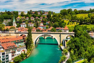 Bern eski şehir merkezi ve Aare, Bern nehri üzerindeki Nydeggbrucke köprüsü manzaralı. Bern, güneşli bir günde Aare Nehri 'nin şehrin etrafında aktığı eski bir kasaba, Bern, İsviçre.