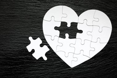 Heart-shaped jigsaw puzzle on color background. Puzzle heart on wooden background. A missing piece of the heart puzzle. Heart shape jigsaw puzzle. Puzzles in the shape of a heart.  clipart