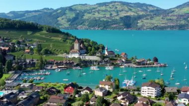 Günbatımında İsviçre kantonundaki Bern kantonunda bulunan Thun Gölü kıyısındaki Spiez Kilisesi ve Kalesi 'nin hava panoramik manzarası, Spiez, İsviçre. İsviçre, Bern kantonunda Thun Gölü 'ndeki Spiez Şatosu.