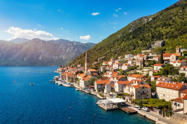 Karadağ 'ın ünlü Kotor Koyu' ndaki tarihi Perast kasabasının mavi gökyüzü ve yaz aylarında bulutlarla dolu güneşli güzel bir günü. Karadağ 'ın Kotor Körfezi' ndeki tarihi Perast kenti yazın.