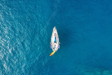 Tropik adanın önündeki kristal berrak turkuaz suya demir atmış, alternatif yaşam tarzı, bir teknede yaşamak. Turkuaz suda demirleyen yatın havadan görünüşü lüks ve zenginliği gösteriyor..