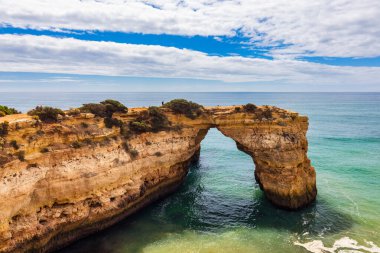 Okyanusun üzerindeki doğal kemer, Arco de Albandeira, Algarve, Portekiz. Praia de Albandeira 'daki taş kemer, Lagoa, Algarve, Portekiz. Portekiz 'in Algarve kentindeki doğal kemer Arco da Albandeira manzarası.
