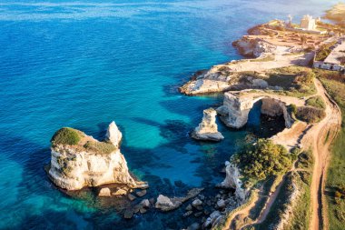 Stunning seascape with cliffs rocky arch and stacks (Faraglioni) at Torre Sant Andrea, Salento coast, Puglia region, Italy. Beautiful cliffs and sea stacks of Sant'Andrea, Salento, Apulia, Italy clipart