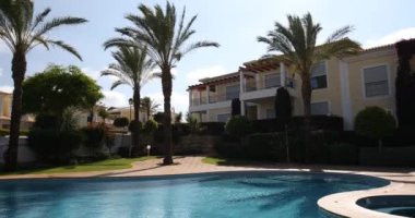 Güneşli bir günde yüzme havuzu, dinlenme yerleri ve palmiye ağaçları, tatil için cennet. Bahçesi palmiye ağaçları ve çiçeklerle dolu arka bahçe yüzme havuzu. Yüzme havuzlu arka bahçe..