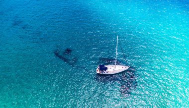 Tropik adanın önündeki kristal berrak turkuaz suya demir atmış, alternatif yaşam tarzı, bir teknede yaşamak. Turkuaz suda demirleyen yatın havadan görünüşü lüks ve zenginliği gösteriyor..