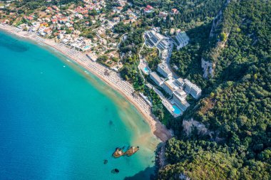 Agios Gordios exotic beach in Corfu island,Greece. Agios Gordios beach, Corfu island, Greece. Panoramic view of the Agios Gordios beach, sandy seashore with beach umbrellas and deck chairs. clipart