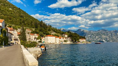 Karadağ 'ın ünlü Kotor Koyu' ndaki tarihi Perast kasabasının mavi gökyüzü ve yaz aylarında bulutlarla dolu güneşli güzel bir günü. Karadağ 'ın Kotor Körfezi' ndeki tarihi Perast kenti yazın.