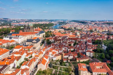 Yazın güneşli bir günde tarihi şato ve canlı çatıların yer aldığı Prag 'ın panoramik manzarası. Prag, Çek Cumhuriyeti 'nin havadan görünüşü şehrin ikonik mimarisini ve kırmızı kiremitli çatılarını gözler önüne seriyor..