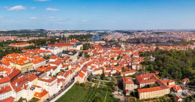 Yazın güneşli bir günde tarihi binaların ve canlı çatıların yer aldığı Prag 'ın panoramik manzarası. Prag, Çek Cumhuriyeti manzarası, şehrin ikonik mimarisini ve kırmızı kiremitli çatılarını gözler önüne seriyor.