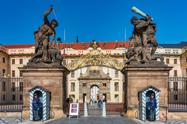 Прага, Чехия - 11 апреля 2024 года: Статуи охраняют вход в Пражский Град в ясный день с посетителями, осматривающими историческое место. Впечатляющие статуи стоят у входа в Пражский град.