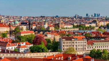 Yazın güneşli bir günde tarihi binaların ve canlı çatıların yer aldığı Prag 'ın panoramik manzarası. Prag, Çek Cumhuriyeti manzarası, şehrin ikonik mimarisini ve kırmızı kiremitli çatılarını gözler önüne seriyor.