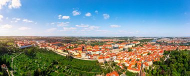 Yazın güneşli bir günde tarihi binaların ve canlı çatıların yer aldığı Prag 'ın panoramik manzarası. Prag, Çek Cumhuriyeti manzarası, Prag ikonik mimarisi ve kırmızı kiremitli çatılar, Çek Cumhuriyeti