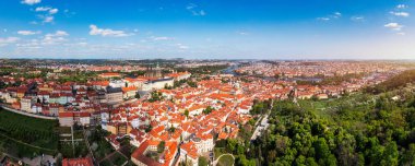 Yazın güneşli bir günde tarihi binaların ve canlı çatıların yer aldığı Prag 'ın panoramik manzarası. Prag, Çek Cumhuriyeti manzarası, şehrin ikonik mimarisini ve kırmızı kiremitli çatılarını gözler önüne seriyor.