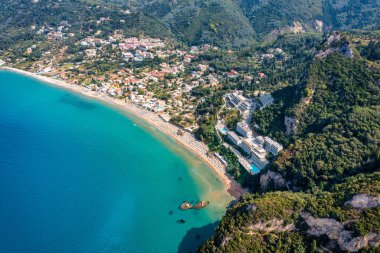 Yunanistan 'ın Korfu adasındaki Agios Gordios egzotik plajı. Agios Gordios plajı, Korfu adası, Yunanistan. Agios Gordios plajının panoramik manzarası, kumlu deniz kıyıları, plaj şemsiyeleri ve şezlonglar..