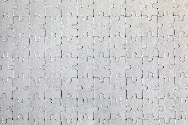 Beyaz yapboz. Renkli arka planda beyaz yapboz parçaları. Renk arkaplanındaki tamamlanmamış beyaz yapboz parçaları. 