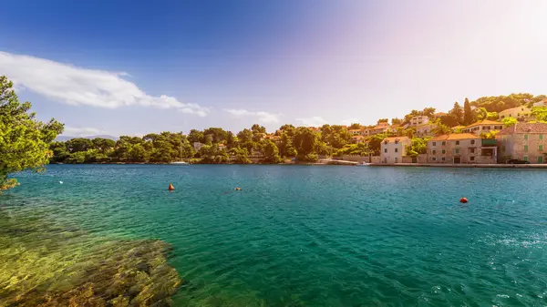 Mavi gökyüzünde güneşli: Splitska köyü Brac Adası, Hırvatistan karşı kilise bina ve palmiye ağacı. 