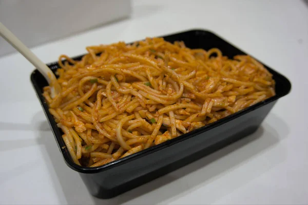 Baharatlı hakka eriştesi tek kullanımlık yemek konteynerinde servis edilir.