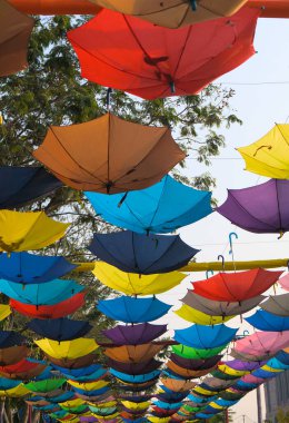 Ters dönmüş renkli gökkuşağı şemsiyeleri sokak sanatı olarak yukarıda asılı. Renkli Görünüm.