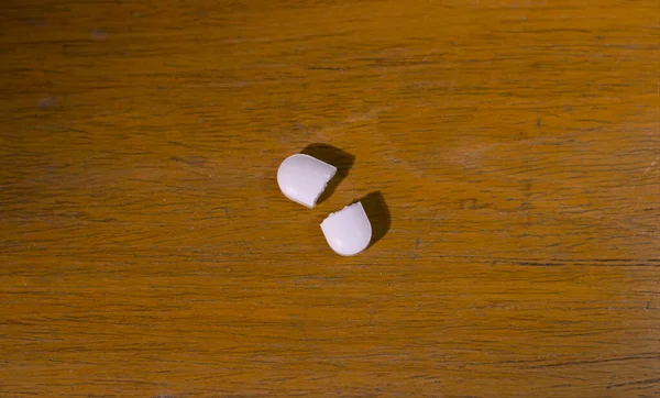 A broken white pill or tablet medicine on a wooden table. Close up