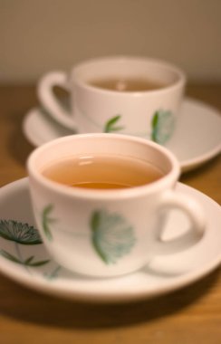 Ahşap bir masada iki fincan çay. Sabah ışığı.