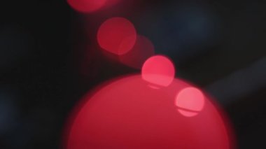 Koyu bir arka planda kırmızı ışık lekeleri var. El kamerasıyla..