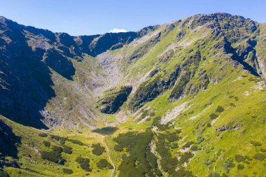 Yeşil vadinin tepesi ve vadi kayalık dağlar ve yoğun yeşilliklerle çevrili.