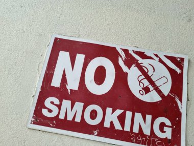 Beyaz bir duvarda sigara içilmediğini gösteren kırmızı bir fotoğraf.