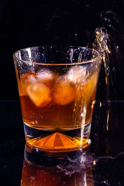 Ein Vertikaler Schuss Eis Spritzt Ein Glas Whiskey Auf Schwarzem — Stockfoto