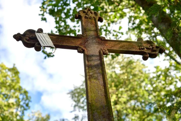 Низкоугольный Снимок Ржавого Металлического Креста Маской Висящей Нем Старом Кладбище — стоковое фото