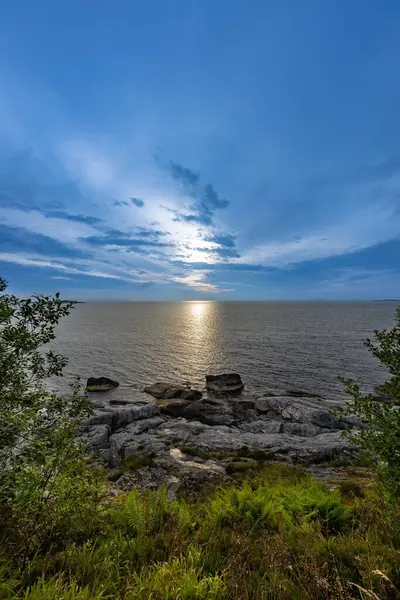 ノルウェーの岩の多い海岸の上の青い夕日の空の垂直ショット — ストック写真