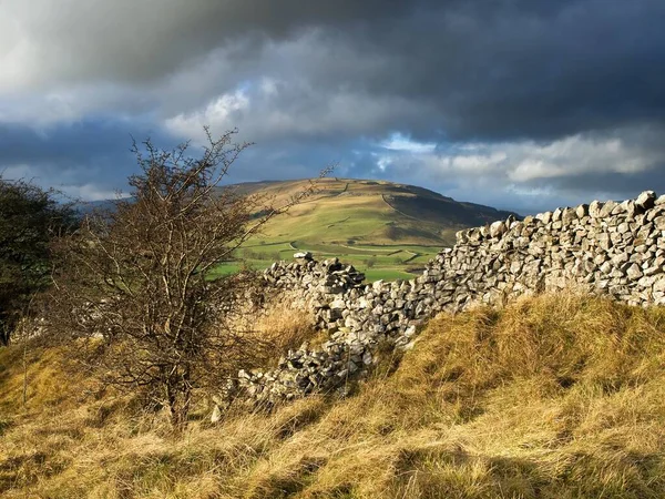 丘の間の田舎の古い石の壁や農業分野上の厚い雲の絵のような景色 — ストック写真