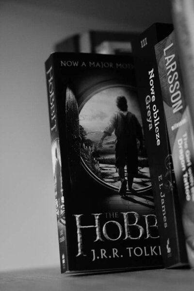 A vertical grayscale closeup of J. R. R. Tolkien's The Hobbit novel on a shelf.