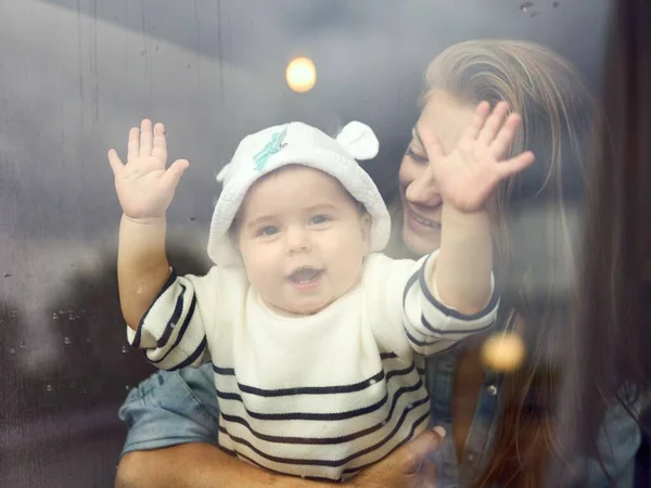 Mor Som Omfamnar Sitt Glada Barn Bakom Glasfönstret — Stockfoto