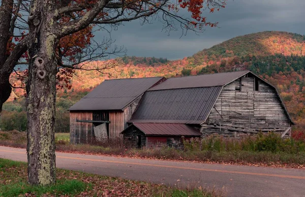 秋にはカラフルな丘を背景にした通り沿いの古い木造納屋 — ストック写真