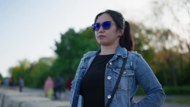 東南アジアの若い女性がサングラスとデニムジャケットをカメラを見て — ストック動画