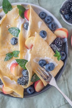 Ev yapımı krep, yaban mersini, şeftali ve ricotta karışımından oluşan lezzetli bir kahvaltı.