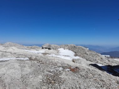 Mavi gökyüzünün altındaki karlı bir dağın köşesinde