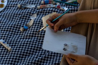 Fırça kullanan ve kağıda resim çizen genç bir kadın.