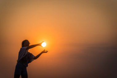 Güneş batarken deniz kenarında güneşi tutan beyaz bir kadın çocuk.