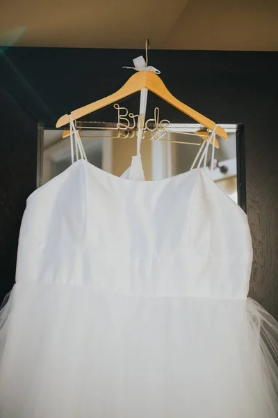 Вертикальный Крупный План Белого Платья Невесты Свисающего Вешалки Перед Зеркалом — стоковое фото