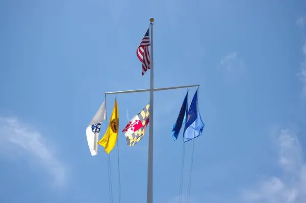 stock image A low-angle of state flags on a metallic cross against clear sunlit sky background