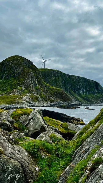一座岩石山和一条装有风力涡轮机的河流的垂直拍摄 — 图库照片