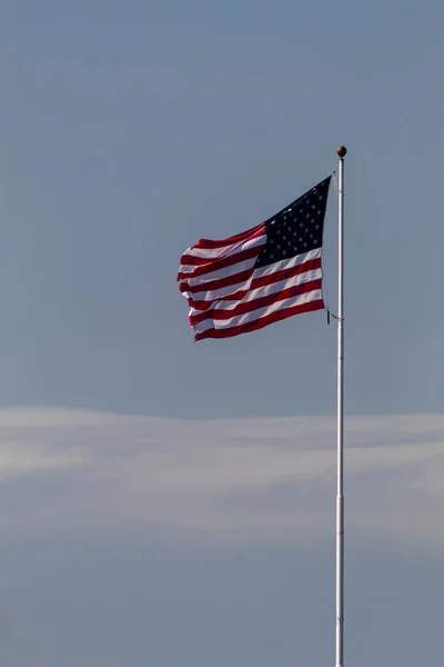 白い極に固定された空気に揺れる米国の旗の垂直ショット — ストック写真