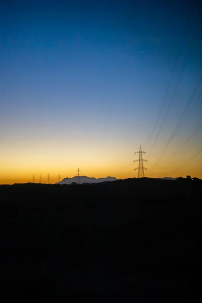 Pionowe Ujęcie Wież Elektrycznych Polu Zachodzie Słońca — Zdjęcie stockowe