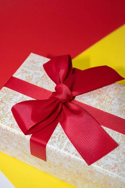 Вертикальный Снимок Маленькой Подарочной Коробочки Бантиком Красочной Поверхности — стоковое фото