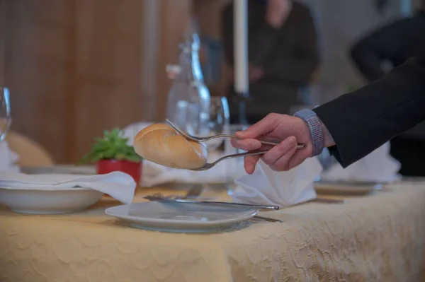 テーブルの近くにスプーンでパンを持っている男性 — ストック写真