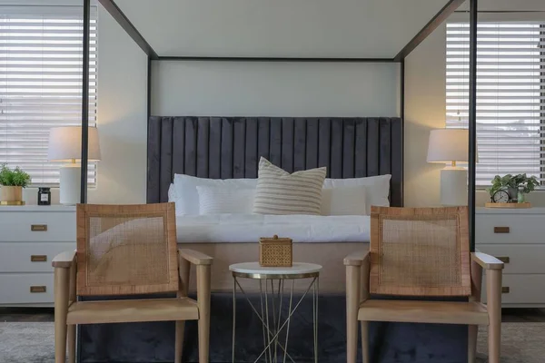 モダンな内装のベッドルームには 白いベッドルームの前に2つの椅子と枕があり 側面には2つのベッドサイドテーブルがあります — ストック写真