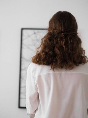 Duvardaki haritaya bakan genç bir kadının dikey bir görüntüsü. Minimalist